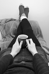 Image showing Woman holding a hot drink, relaxing with her feet up