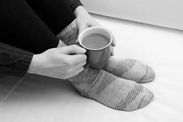 Image showing Woman holding a hot drink, wearing warm knitted socks