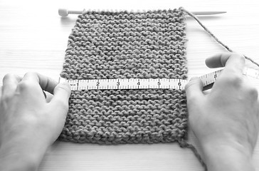 Image showing Two hands measuring knitting in inches