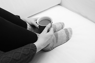 Image showing Woman's hands holding a hot beverage, sitting on a couch