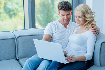 Image showing Young couple sitting sharing a laptop computer