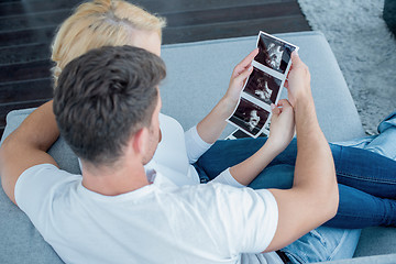 Image showing Sweet Couple on Couch Looking Ultrasound Photos