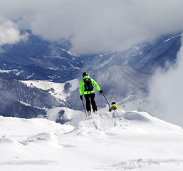 Image showing Freeriders on off-piste slope and mountains in haze