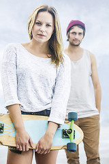 Image showing girl with a skateboard stands in front of a boy