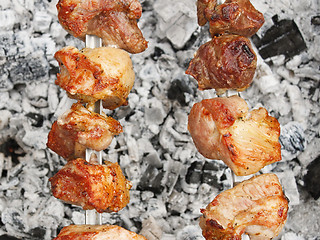 Image showing Shish kebab on metal skewers over charcoal with ash