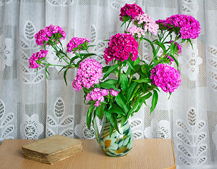 Image showing A bouquet of flowers carnations on the table in a glass vase.