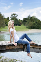 Image showing Blond woman sitting on a jetty