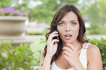 Image showing Shocked Young Adult Female Talking on Cell Phone Outdoors