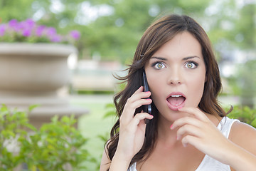 Image showing Shocked Young Adult Female Talking on Cell Phone Outdoors