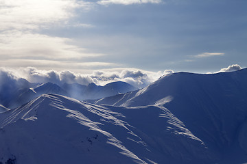 Image showing Snowy mountains in mist at sun evening