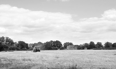 Image showing Tractor baling straw in a farm field 