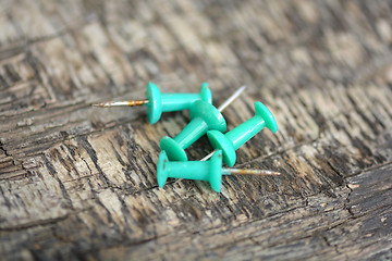 Image showing green push pins on old wooden background