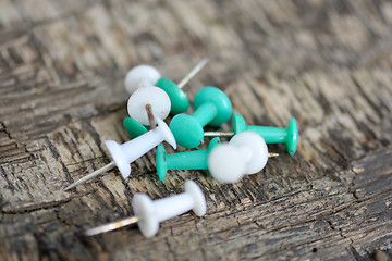 Image showing old green and white push pins on old wooden background