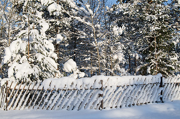 Image showing The wooden fence filled up by a snow in a countryside.