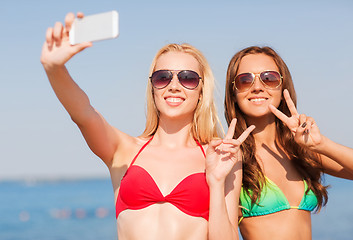 Image showing two smiling women making selfie on beach