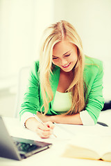 Image showing smiling student girl writing in notebook