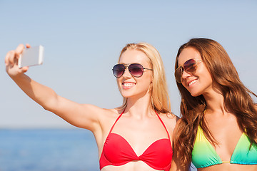 Image showing two smiling women making selfie on beach
