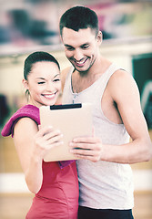 Image showing two smiling people with tablet pc in the gym