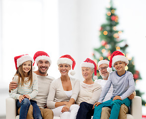 Image showing happy family in santa helper hats sitting on couch