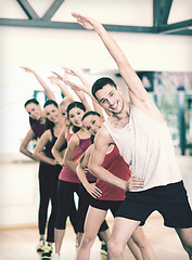 Image showing group of smiling people stretching in the gym