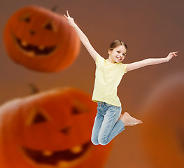 Image showing smiling girl jumping over pumpkins background