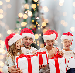 Image showing happy family in santa helper hats with gift boxes