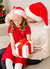 Image showing smiling father surprises daughter with gift box