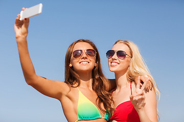 Image showing two smiling women making selfie on beach