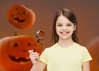 Image showing smiling girl in glasses over pumpkins background