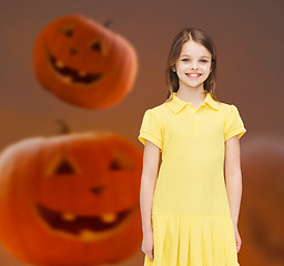 Image showing smiling girl in dress over pumpkins background