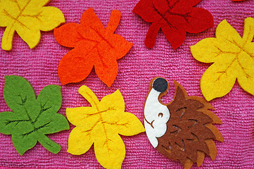 Image showing Hedgehog and colorful Maple leaves out of felt on a pink fabric 