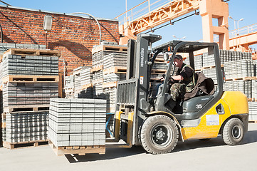 Image showing Driver on lift truck loads products of plant