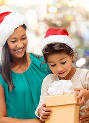 Image showing happy mother and girl in santa hats with gift box