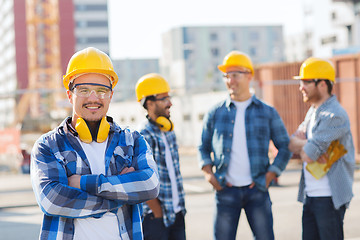 Image showing group of smiling builders in hardhats outdoors