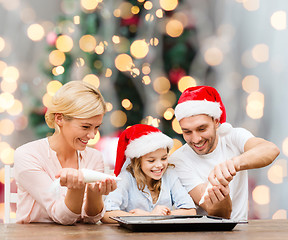 Image showing happy family in santa helper hats cooking