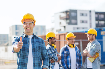 Image showing group of smiling builders in hardhats outdoors