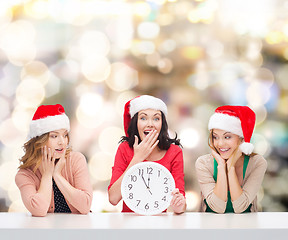 Image showing smiling women in santa helper hats with clock