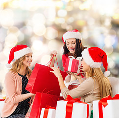 Image showing smiling young women in santa hats with gifts
