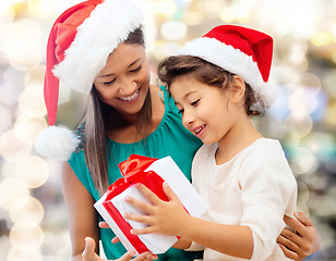 Image showing happy mother and girl in santa hats with gift box