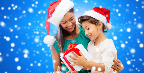 Image showing happy mother and girl in santa hats with gift box