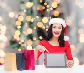 Image showing smiling woman in santa hat with bags and tablet pc