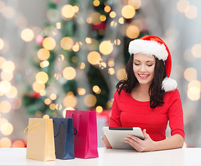 Image showing smiling woman in santa hat with bags and tablet pc