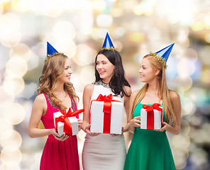 Image showing smiling women in party caps with gift boxes