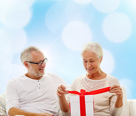 Image showing happy senior couple with gift box at home