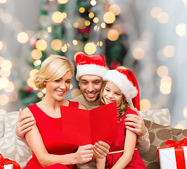 Image showing happy family in santa hats with greeting card