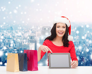 Image showing smiling woman in santa hat with bags and tablet pc