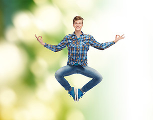 Image showing smiling young man jumping in air