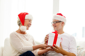 Image showing happy senior couple in santa hats with gift box