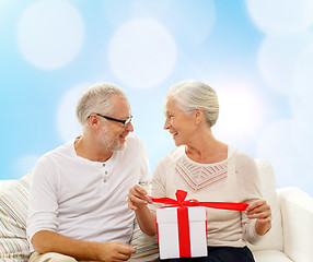 Image showing happy senior couple with gift box at home