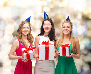 Image showing smiling women in party caps with gift boxes